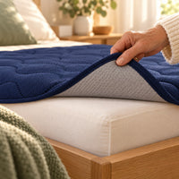 Dessous anti-glisse du drap protège-matelas bleu marine, soulevé sur un coin de matelas