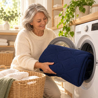 Une femme sort de la machine à laver le drap protège-matelas bleu marine, lavable en machine