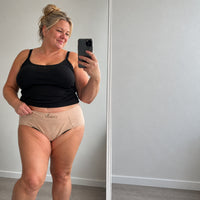 Femme en selfie miroir portant la culotte absorbante Vostery beige sous un haut noir