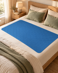 Drap protège-matelas imperméable bleu marine clair posé sur un lit en lin dans une chambre chaleureuse